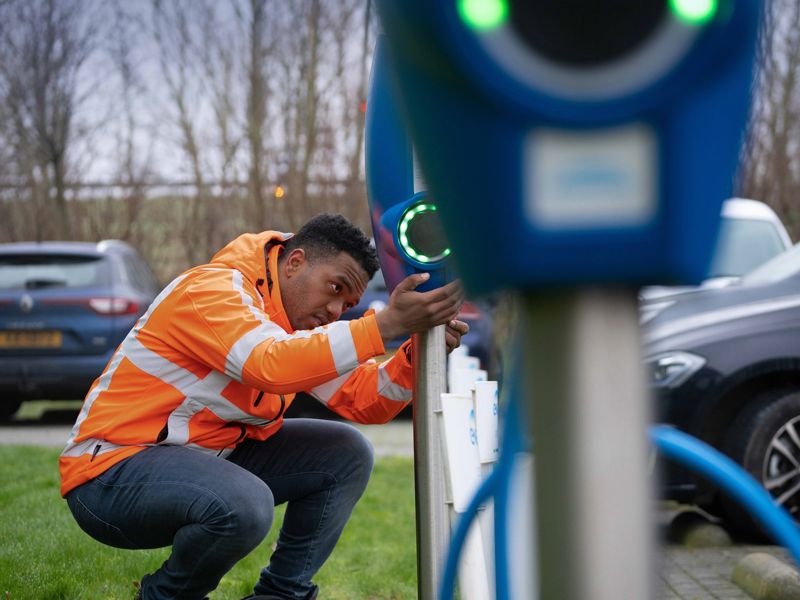 oplossingen-e-mobility-man-oranje-hesje-gebukt-bij-laadpaal-dordrecht-2000x1180.jpg