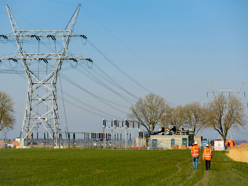 oplossingen-e-grid-solutions-collegas-lopen-op-veld-met-elektriciteitspaal-2000x1333.jpg